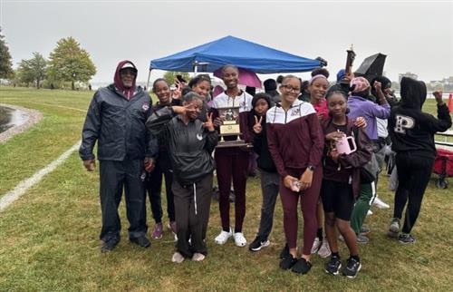 Girls cross country team posing with coach and trophy